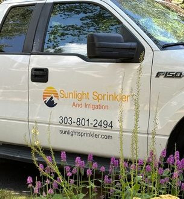 sunlight sprinkler work truck behind flowers